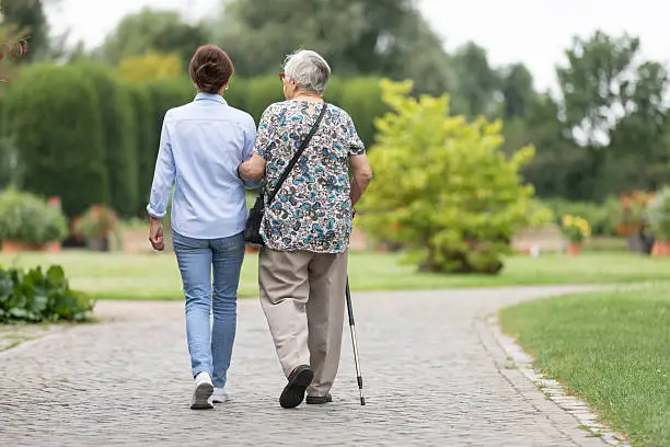 Adult child supporting an older parent during a walk